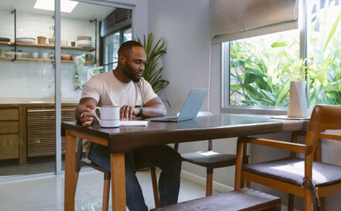 Persona trabajando desde casa en marketing de afiliación con portátil y café